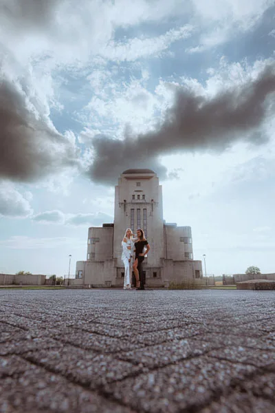 Paarshooting vor einem imposanten Monumentalbau unter bewölktem Himmel.