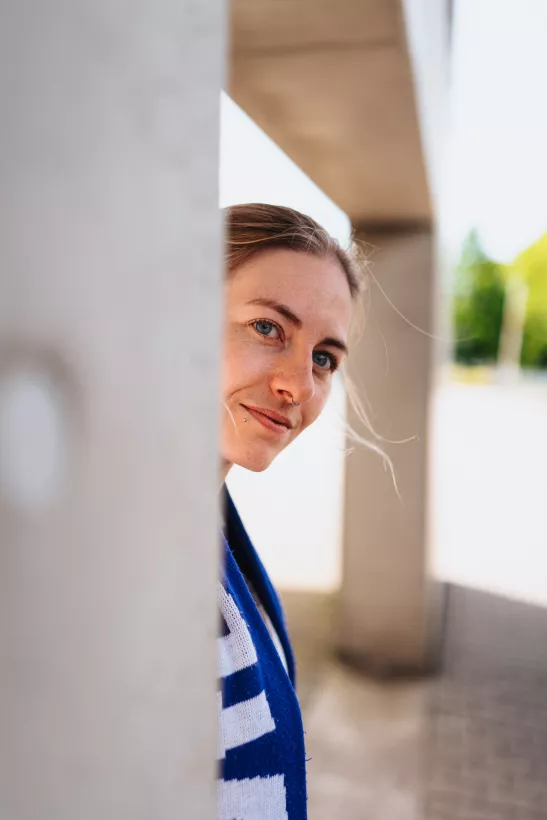 Portrait einer Frau mit blauen Augen hinter einer Betonstruktur