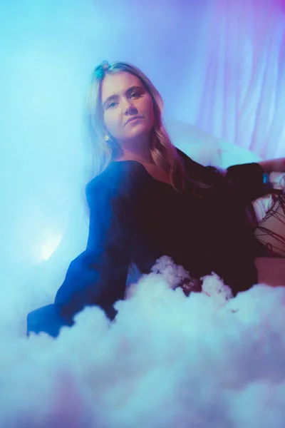 Portrait einer Frau in blauem und violettem Licht inmitten von Nebelschwaden