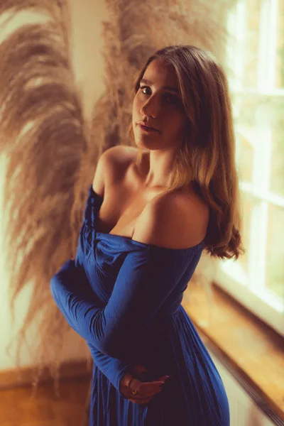 Portrait einer Frau im blauen schulterfreien Kleid vor weichem Pampasgras.
