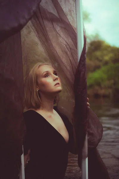 Portrait einer Frau mit Blick nach oben hinter dunklem, transparentem Stoff