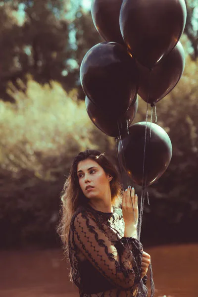 Portrait einer Frau mit großen schwarzen Luftballons vor einem unscharfen Hintergrund.