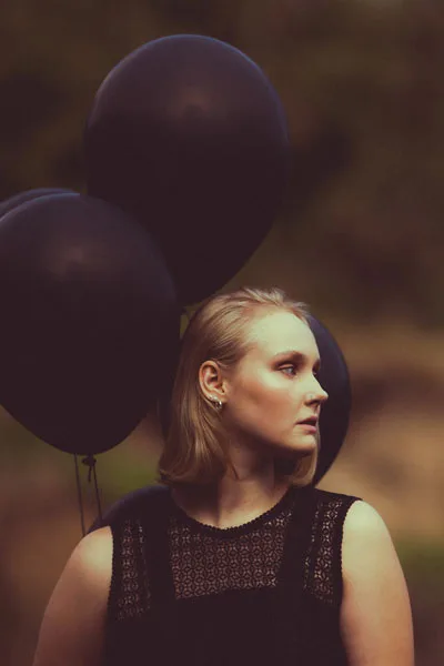 Portrait einer Frau im Profil mit großen schwarzen Luftballons.
