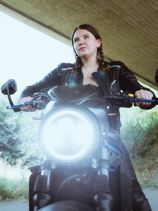 Low-Angle-Portrait einer Frau in schwarzer Lederjacke auf einem Motorrad