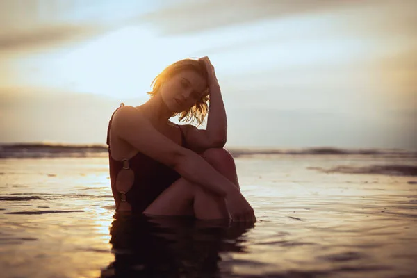 Portrait einer Frau im seichten Meereswasser bei Sonnenuntergang.