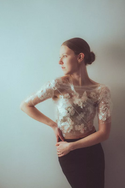 Portrait einer Frau in einem transparenten Oberteil mit weißen Blumenapplikationen