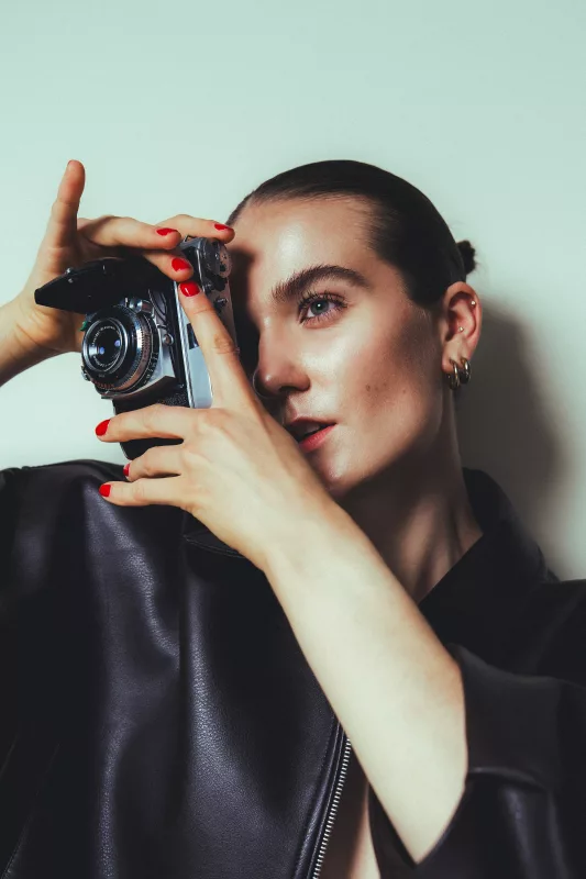 Portrait einer Frau mit Vintage-Kamera und schwarzer Lederjacke