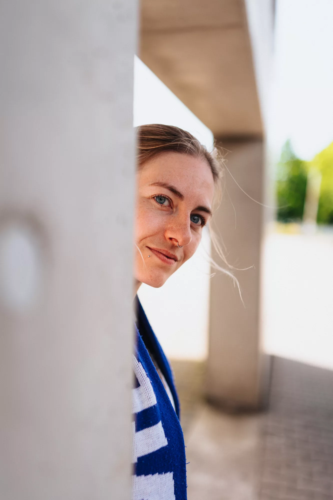 Portrait einer Frau, die hinter einer weißen Säule hervorschaut
