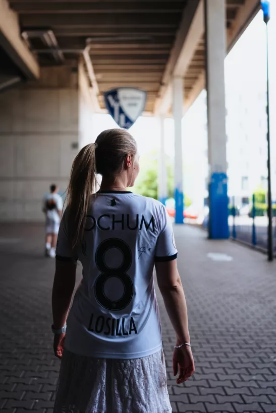 Portrait einer Frau von hinten in einem weißen Sporttrietkot mit heller Lichtstimmung unter einer Brücke