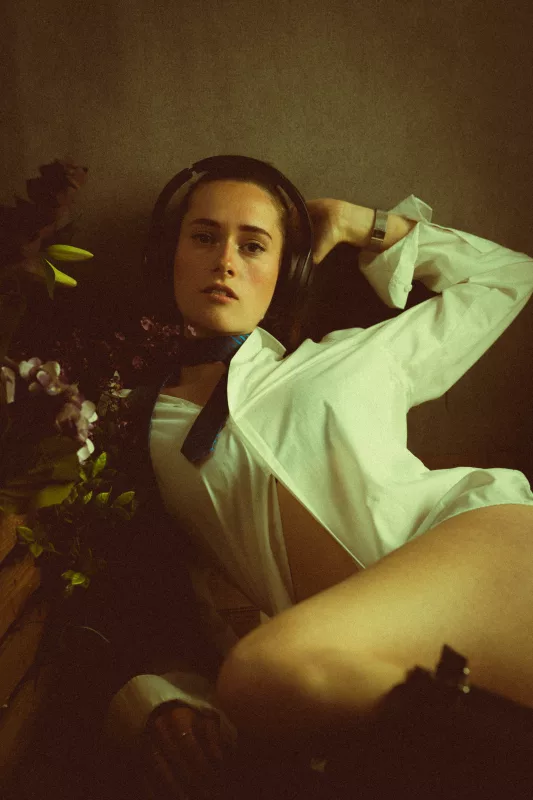 Portrait einer jungen Frau mit großen Kopfhörern und einem weißen Hemd