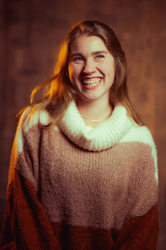 Portrait einer lachenden Frau in einem mehrfarbigen Strickpullover