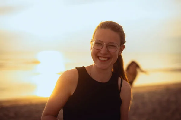 Portrait einer lächelnden Frau mit Brille im warmen Abendlicht