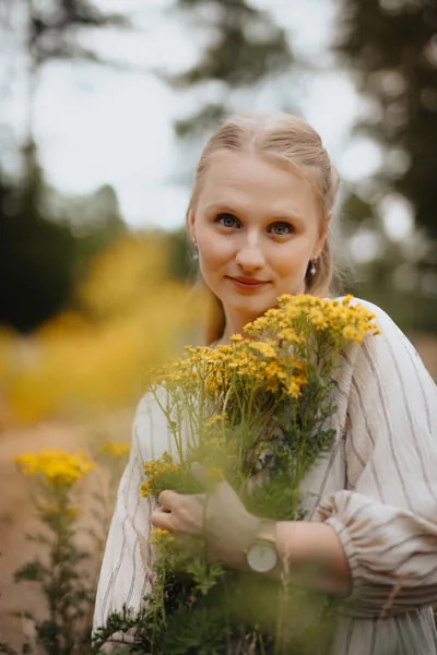 Natürliches Portrait einer lächelnden Frau mit einem Strauß gelber Wildblumen