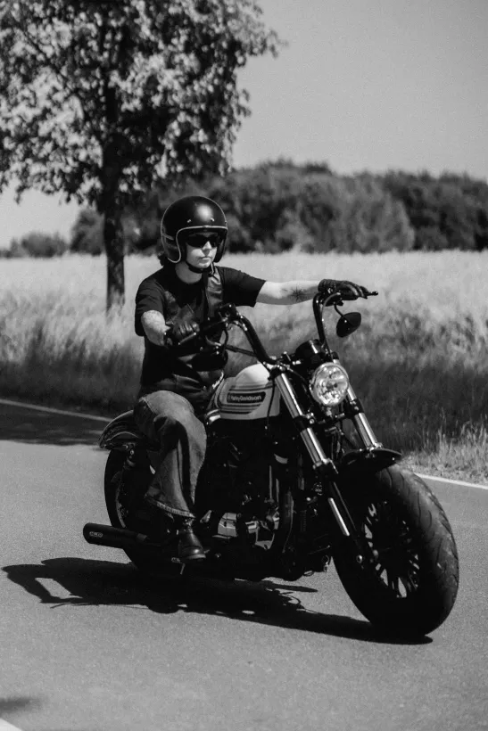 Schwarz-Weiß-Fotografie eines Motorradfahrers auf einer Landstraße