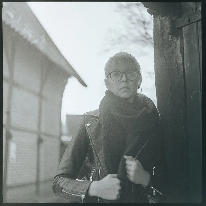 Schwarz-weißes Portrait einer Frau mit Brille und dunklem Schal