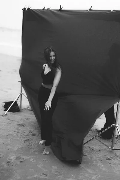 Schwarz-weiß Portrait einer Frau vor einem dunklen Hintergrund am Strand.