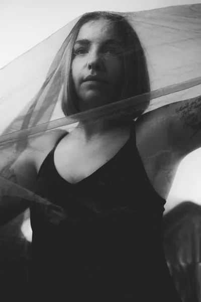 Schwarz-weiß Portrait einer Frau hinter einem zarten, transparenten Schleier.