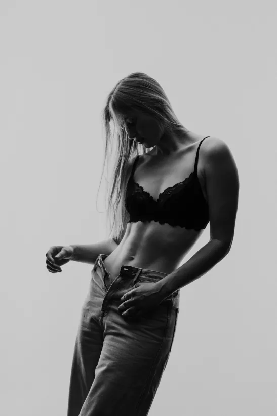 Schwarz-weiß Studiofoto einer Frau in schwarzer Spitze und Jeans
