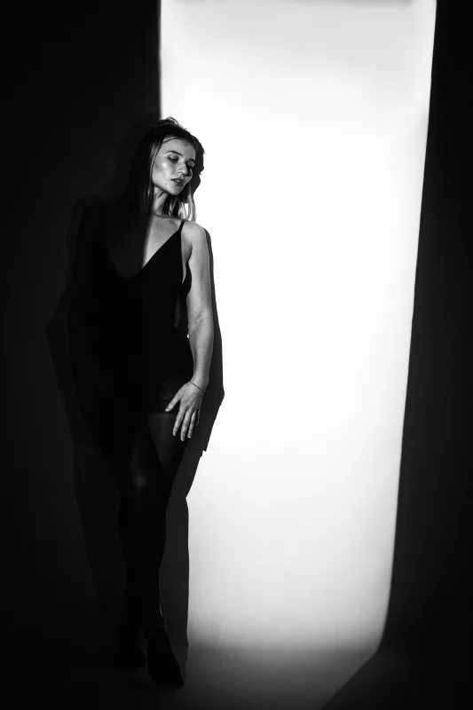 Schwarz-weiß Studioportrait einer Frau im harten Lichtkegel.