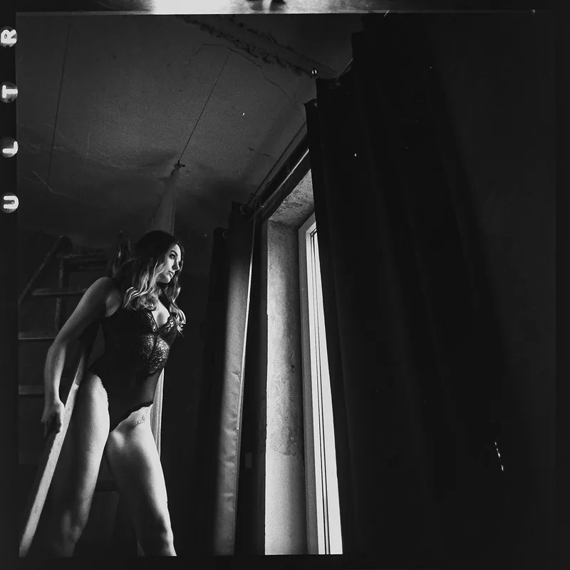 Schwarz-weißes Boudoirportrait einer Frau in einem dunklen Body bei kontrastreichem Lichteinfall.