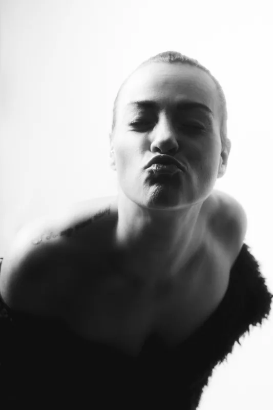 Schwarz-weißes Porträt einer Person mit kurzen Haaren und geschürzten Lippen.