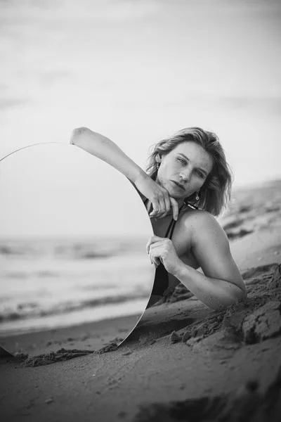 Schwarz-weißes Portrait einer Frau am Strand, eingerahmt von einem kreisförmigen Element.