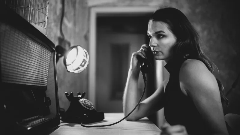 Schwarz-weißes Portrait einer Frau, die an einem Vintage-Telefon spricht.