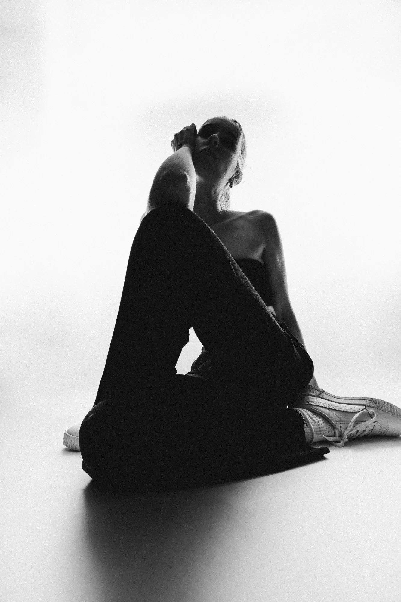 Schwarz-weißes Studioportrait einer sitzenden Frau in Silhouette.