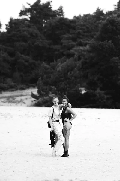 Schwarzweiß-Portrait von zwei Frauen am Sandstrand vor einer Waldkulisse