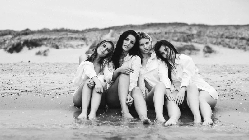 Schwarzweiß-Portrait von vier jungen Frauen am Strand.