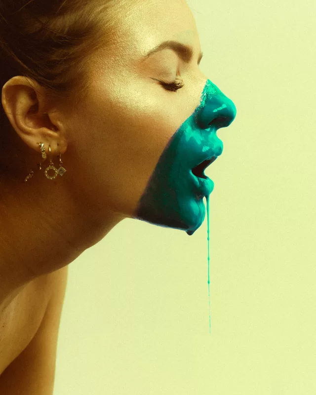 Seitenprofil einer Frau mit blau fließender Farbe auf Nase und Mund.