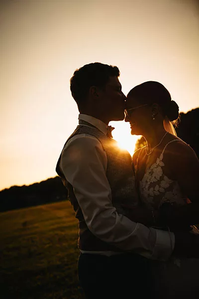 Silhouette eines Brautpaares im Gegenlicht der untergehenden Sonne.
