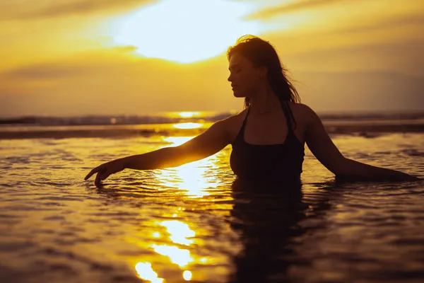 Silhouette einer Frau im Meer bei Sonnenuntergang
