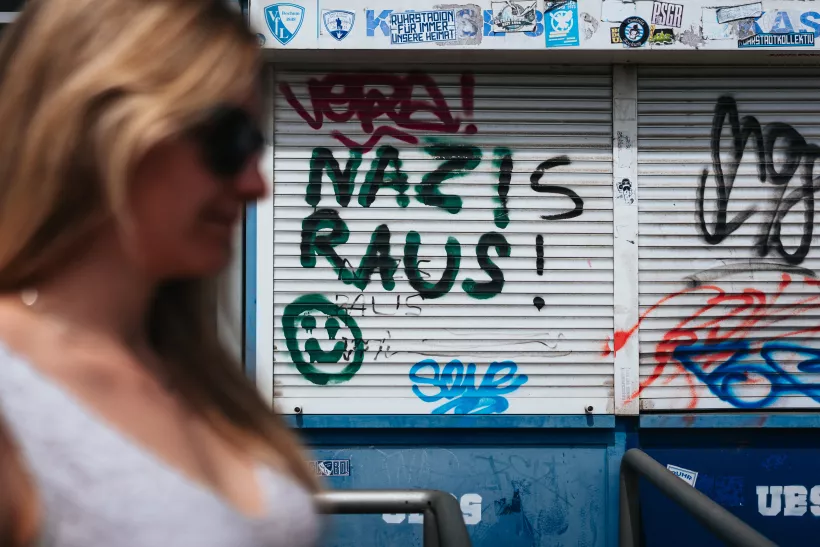 Streetfotografie einer unscharfen Frau vor einer mit Graffiti beschmierten Metallrolllade