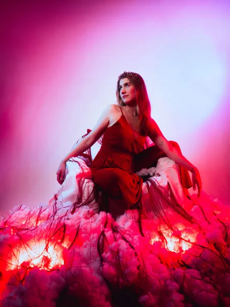 Studiofoto einer Frau im roten Kleid zwischen rosa Tüllwolken
