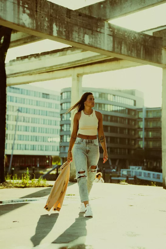 Urbanes Lifestyle-Portrait einer Frau in heller Kleidung unter Betonstrukturen