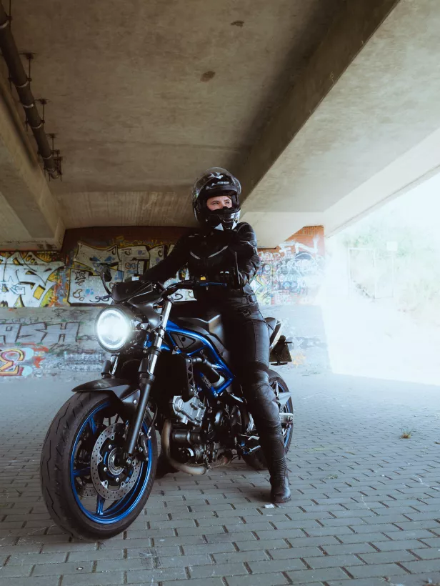 Urbanes Lifestyle-Portrait einer Person in schwarzer Lederkluft auf einem Motorrad vor einer Graffitiwand