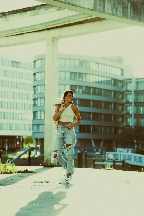 Urbanes Streetstyle-Portrait einer Frau in weißem Top und hellen Jeans