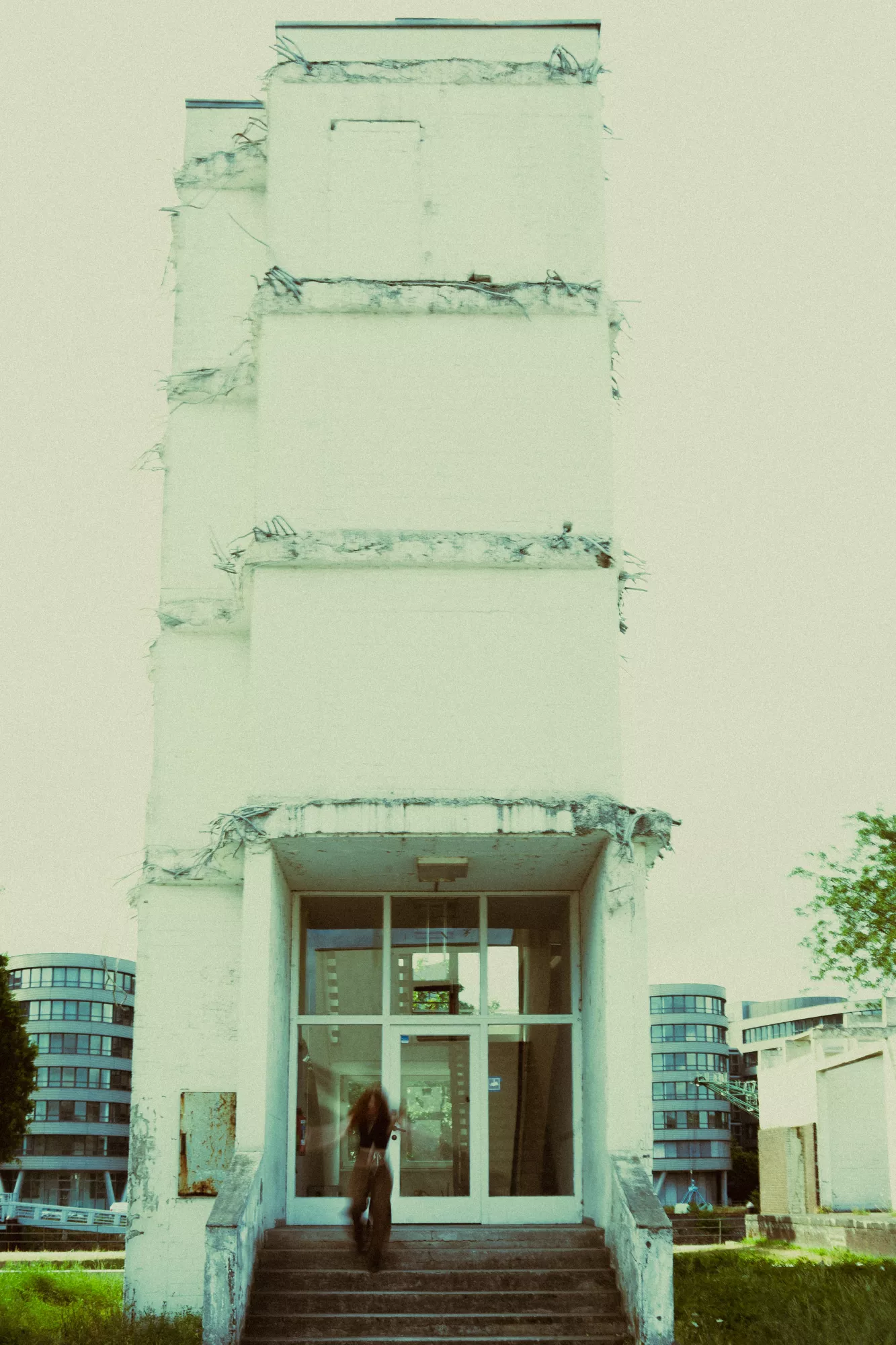 Architekturfotografie eines hohen, weißen Gebäudes mit einer Person im Eingangsbereich