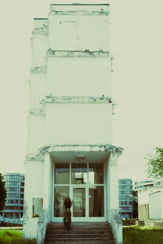Architekturfotografie eines hohen, weißen Gebäudes mit einer Person im Eingangsbereich