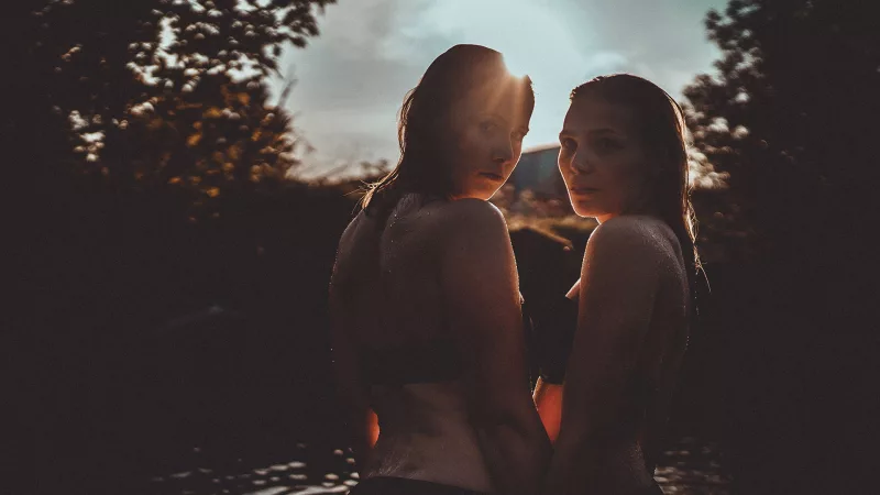 Zwei Frauen blicken im warmen Gegenlicht über ihre Schultern.