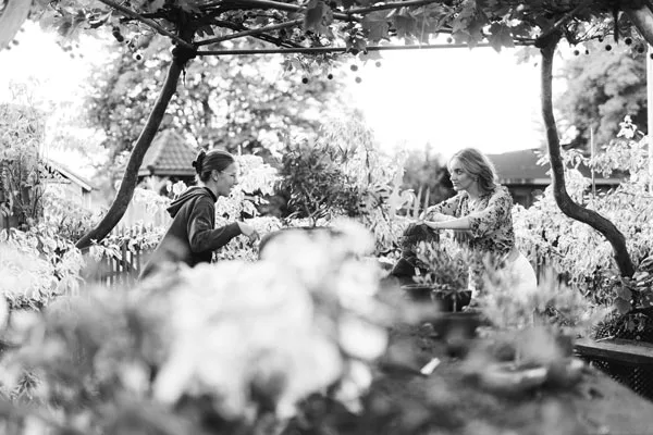 Zwei Frauen bei der Gartenarbeit unter einer hölzernen Pergola.
