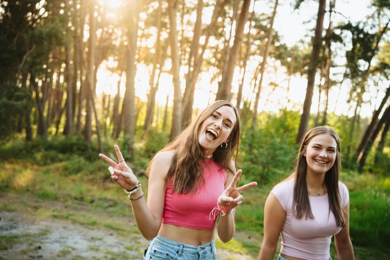 Zwei lachende junge Frauen in einem sonnendurchfluteten Wald